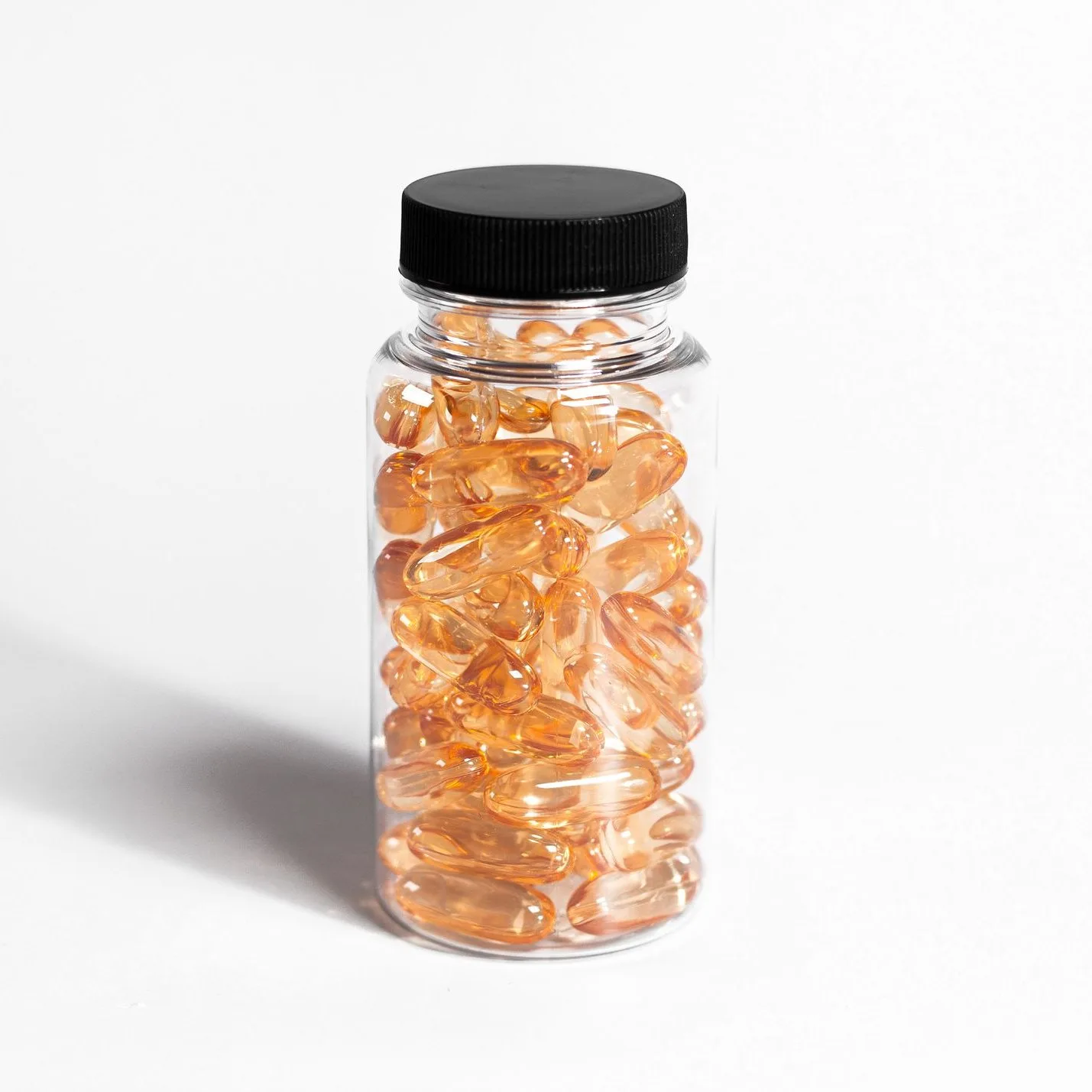 Clear jar of amber softgels