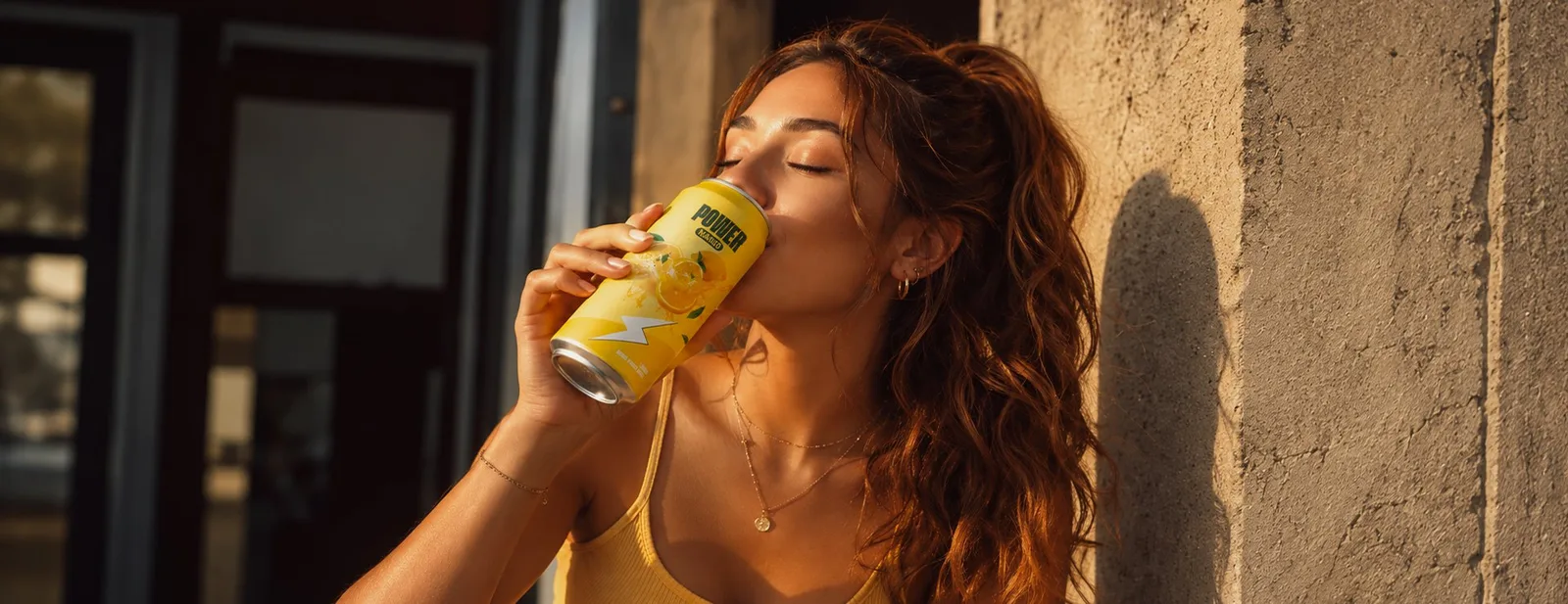 A woman drinking from a can in the sun