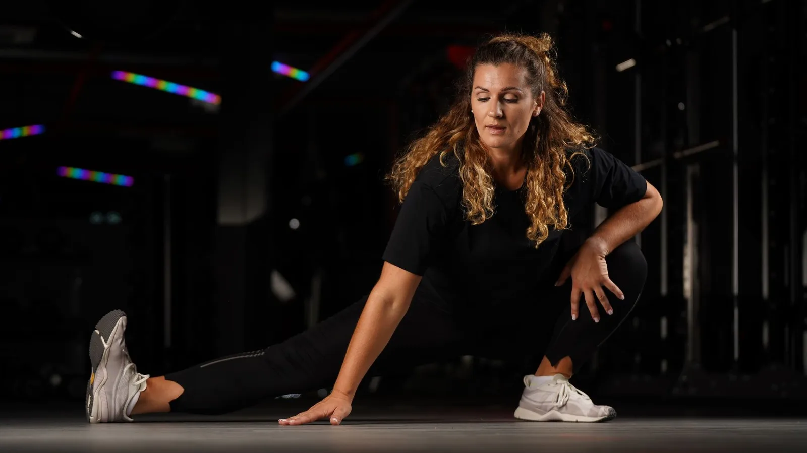 A woman stretching in a dark gym