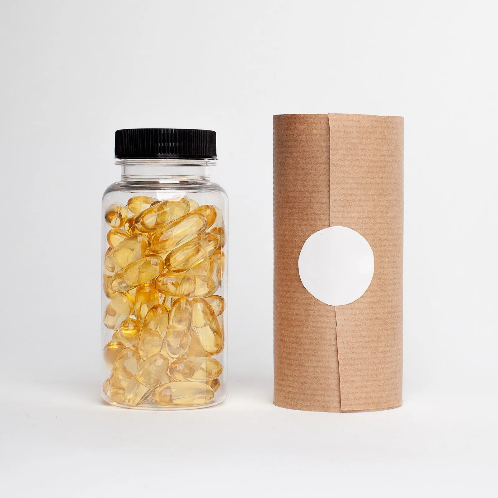 Clear jar of softgels beside a paper tube