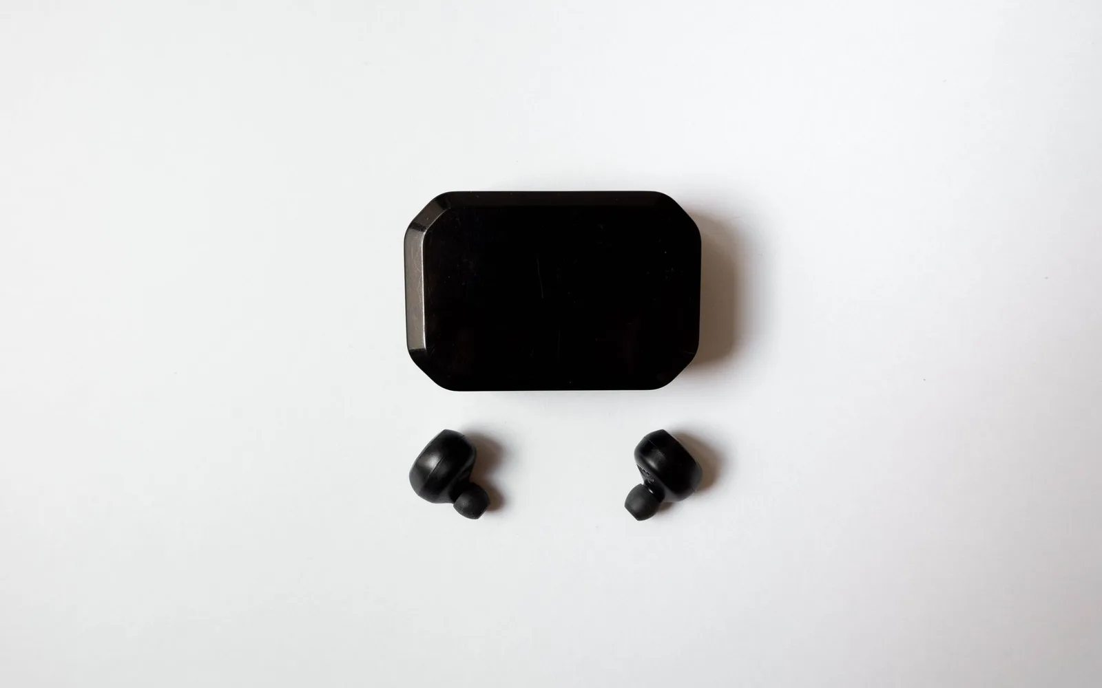 Black earphones and their case on white
