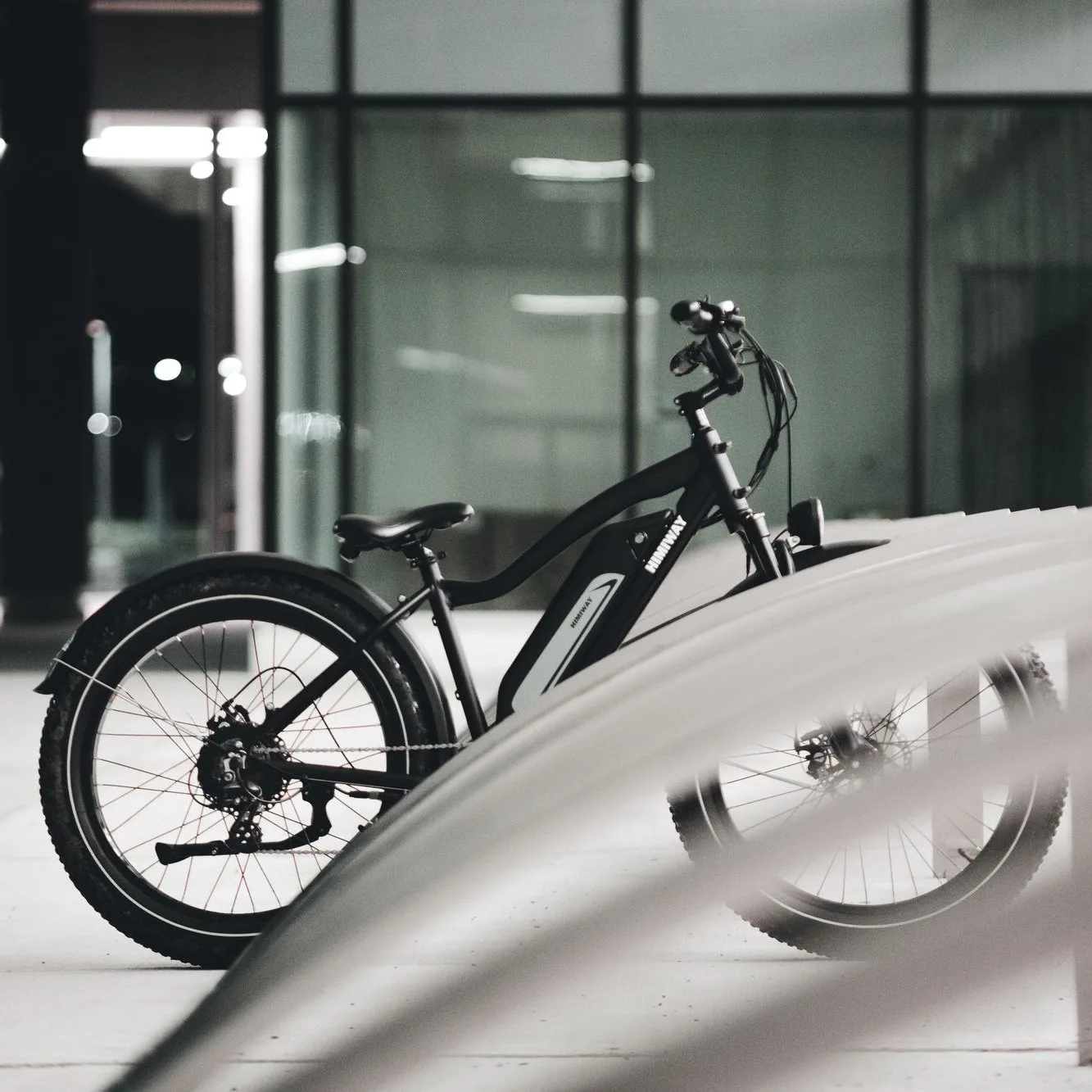 Black e-bike with wide tyres by a glass building