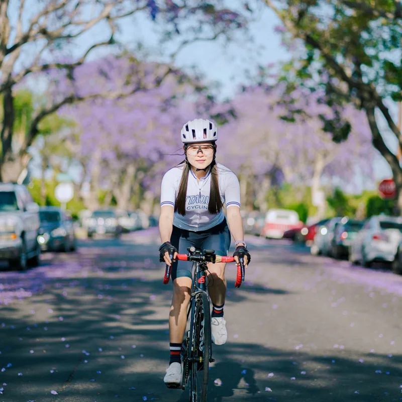 A cyclist riding under purple trees