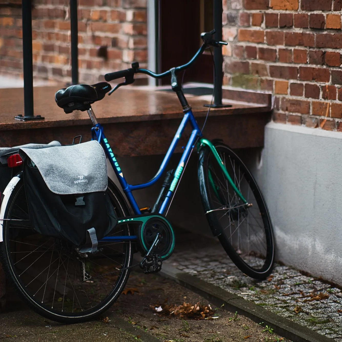 Blue bike with a pannier by a brick wall