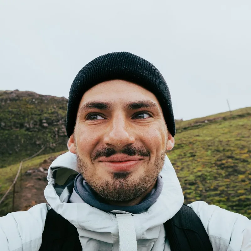 A hiker in a white jacket on a green hill