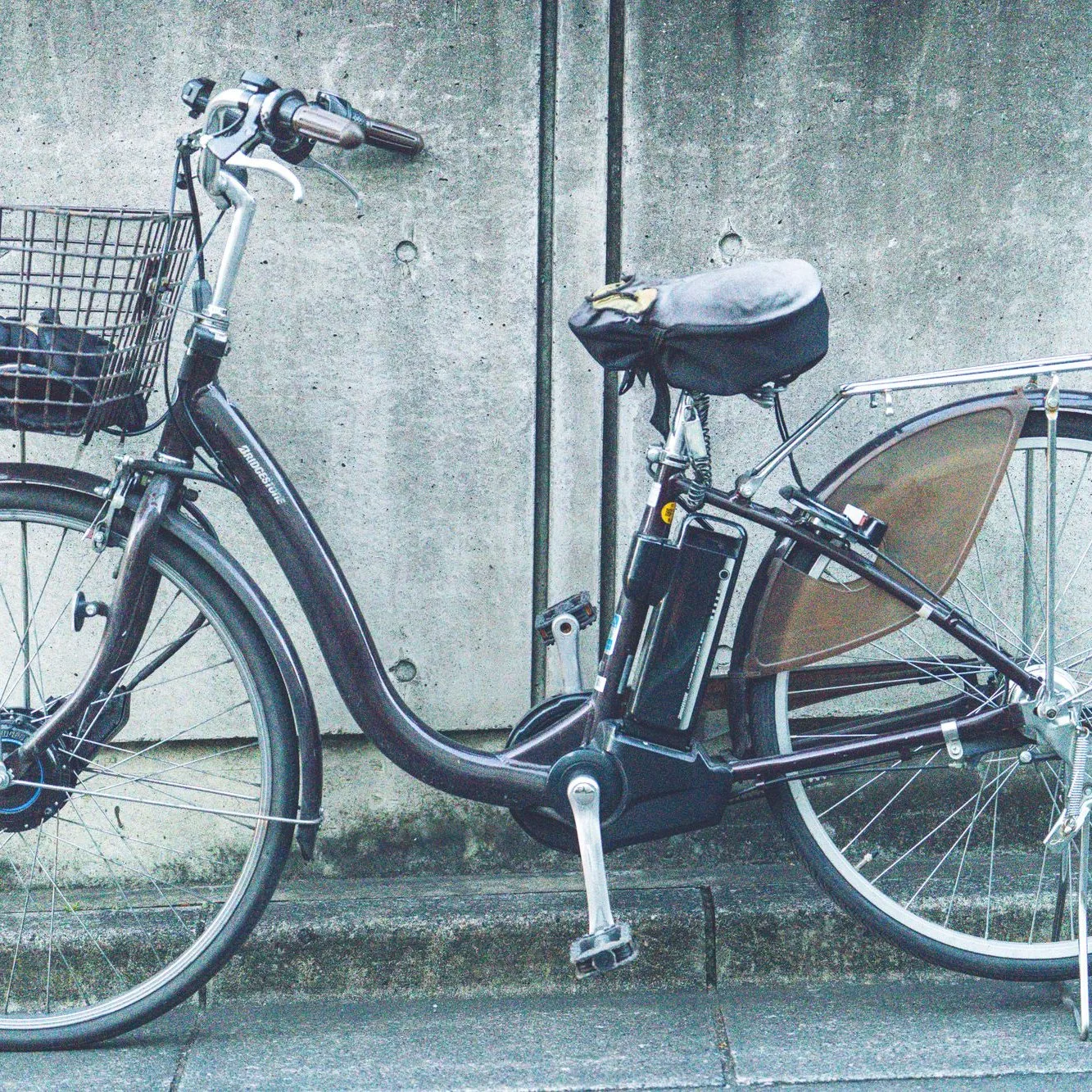 Step-through e-bike with a basket against a concrete wall
