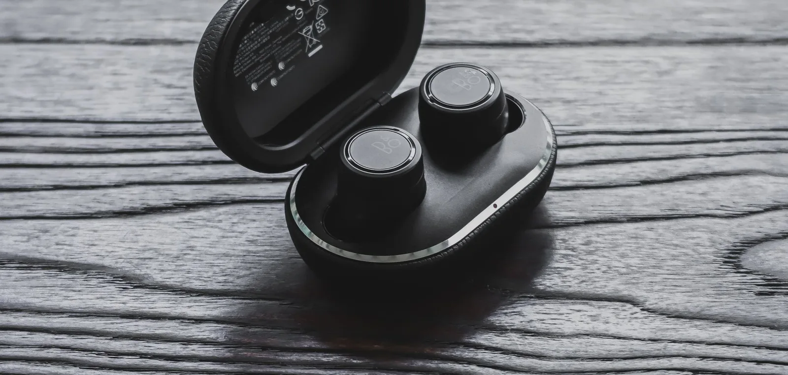 Black earphones in their case on grey wood