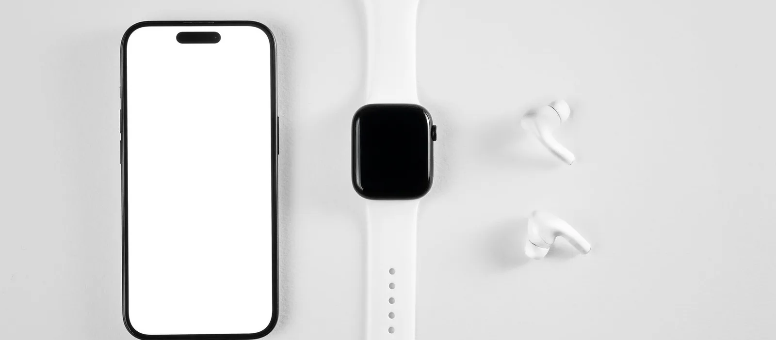 Phone, watch and earbuds on a white desk