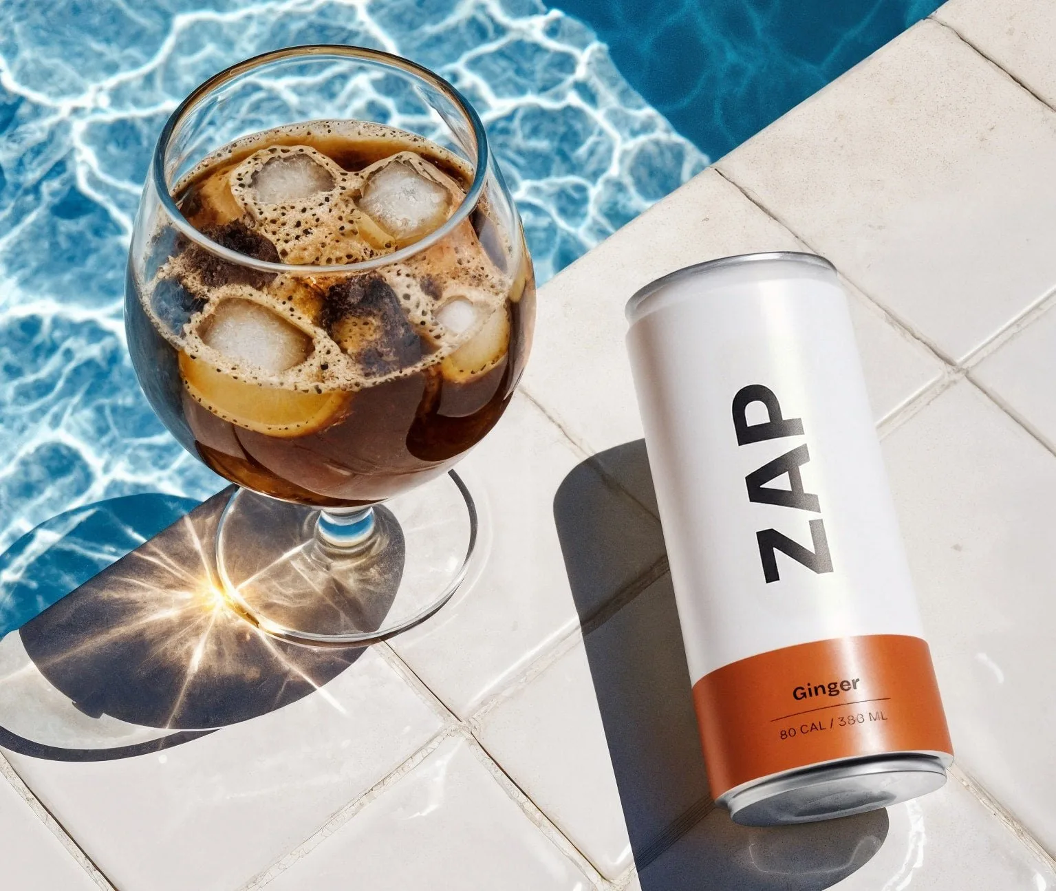 A can of ginger cold brew by an iced glass at the pool
