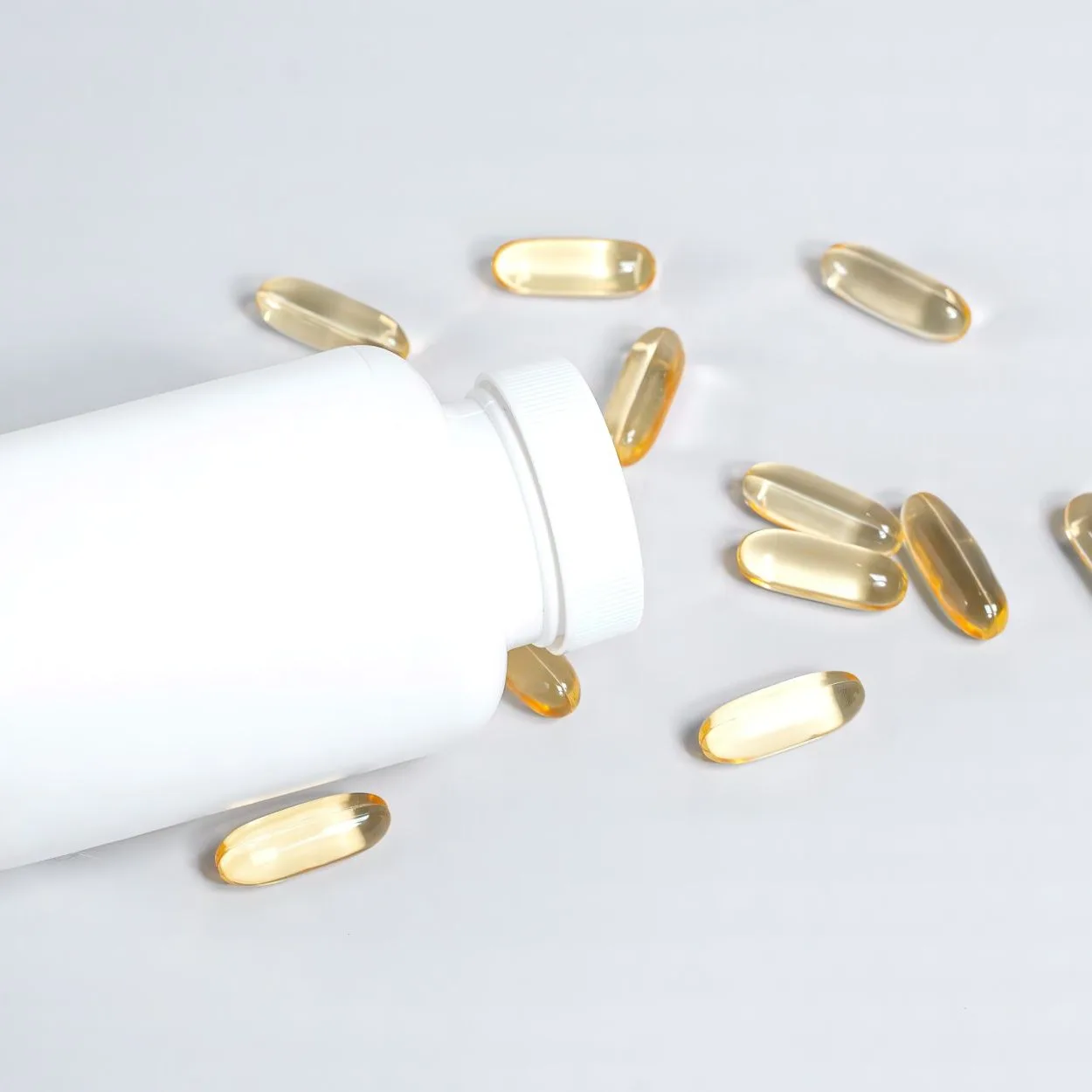 Softgels beside a white bottle