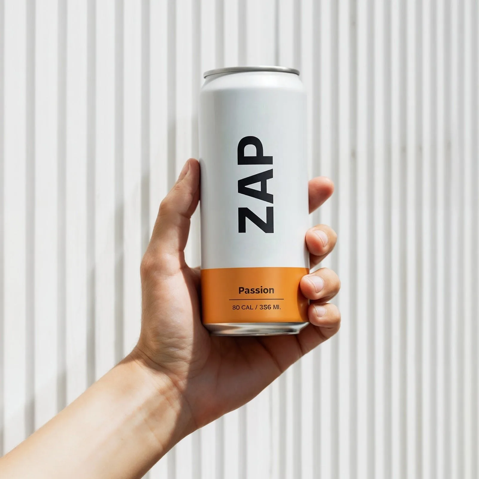 A hand holding a can of passion cooler